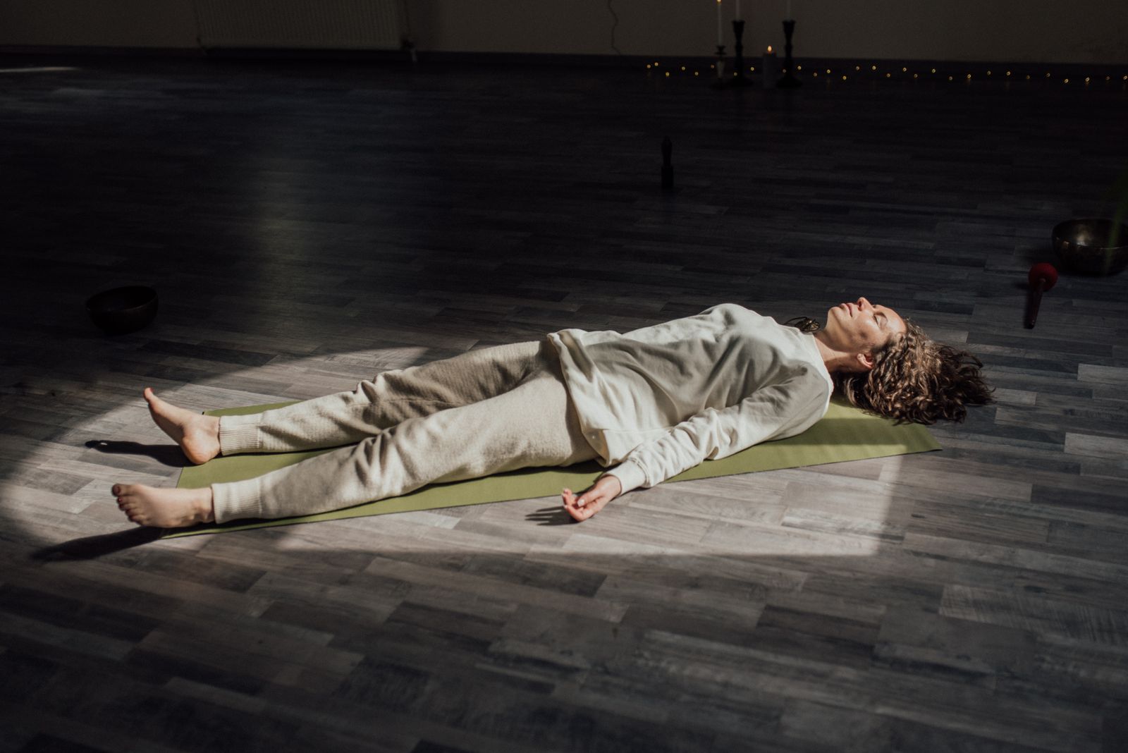 Yoga for anxiety and stress relief - resting in Savasana with candles and singing bowls